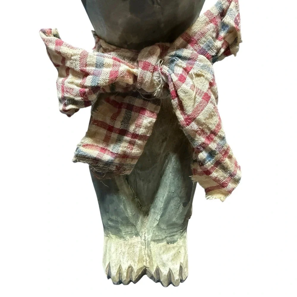 hand-carved wooden cat figurine with a painted finish and a plaid cloth scarf.